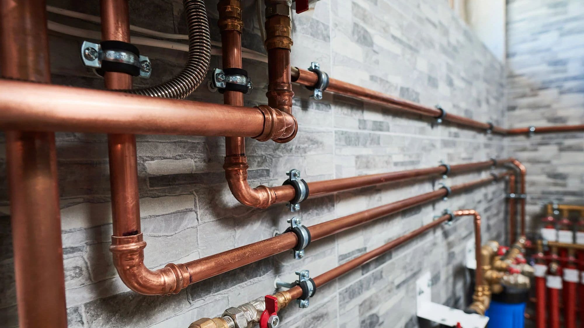 Copper supply lines, valves and manifolds running along a residential wall